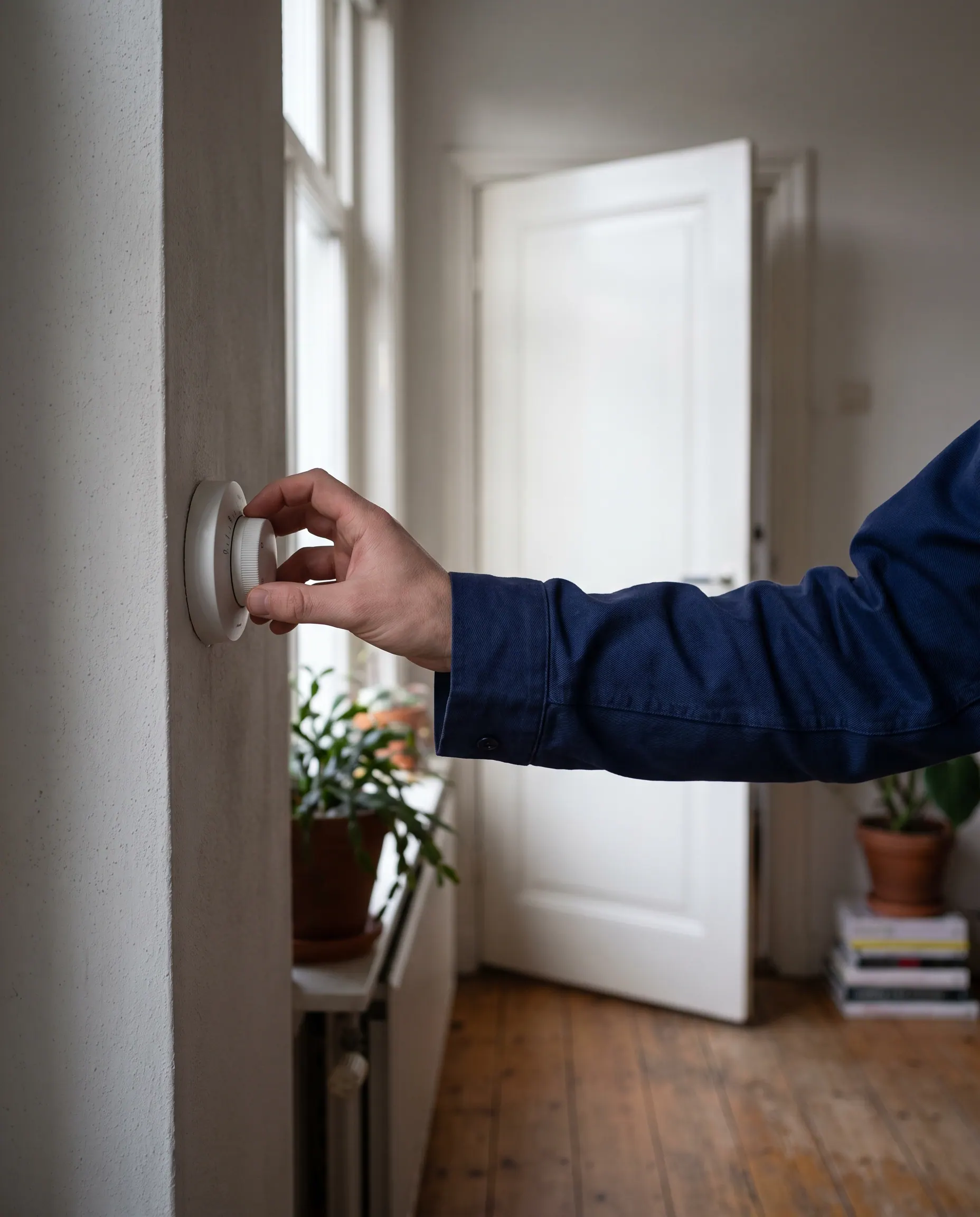 Hand stelt de thermostaat in op een lage, vorstveilige temperatuur